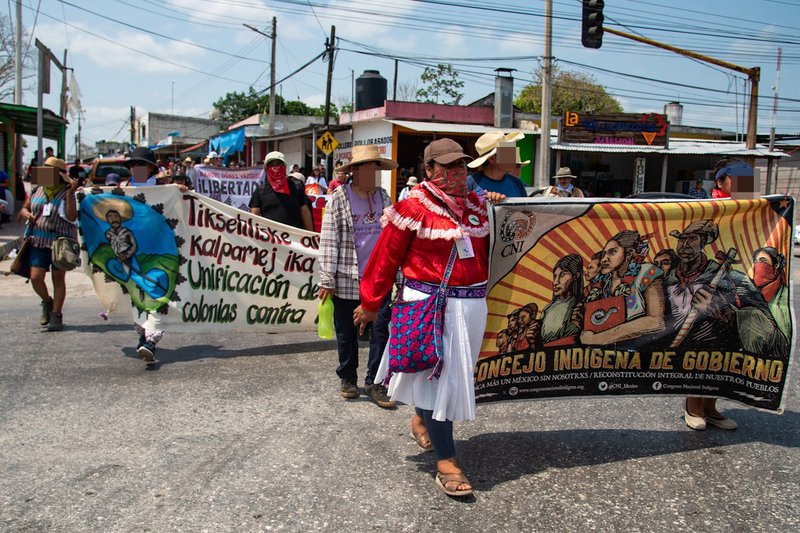 Personen mit traditioneller Kleidung der Otomíes laufen bei einer Demonstration mit einem Banner des CNI