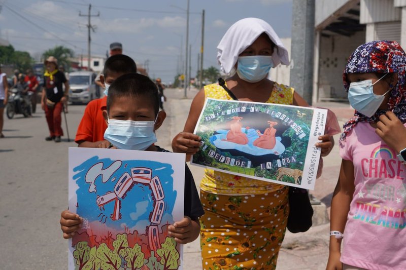 Eine Frau und ein Junge mit einem Plakat geen den Tren Maya