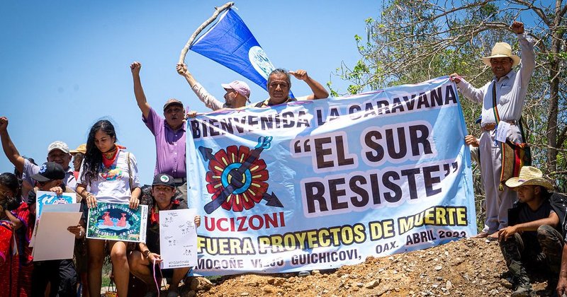 Personen halten ein Banner mit der Aufschrift »UCIZONI bienvenida la caravana El Sur Resiste«