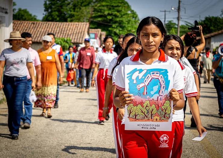 Jugendliche in Schuluniform trägt ein Plakat gegen den Tren Maya