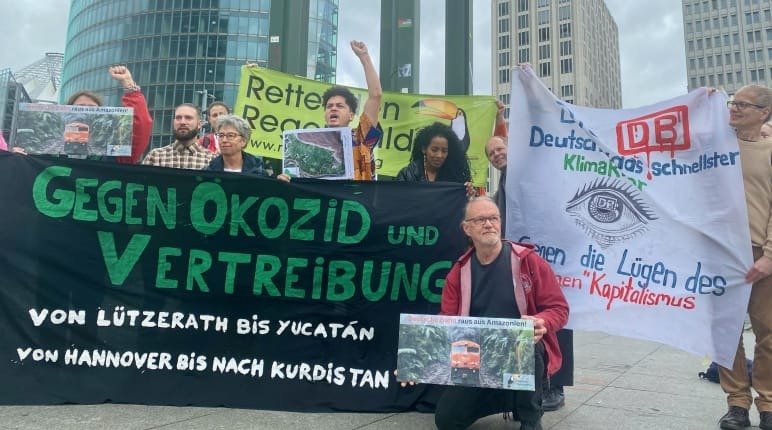 Eine Gruppe steht mit Bannern vor dem DB Tower in Berlin