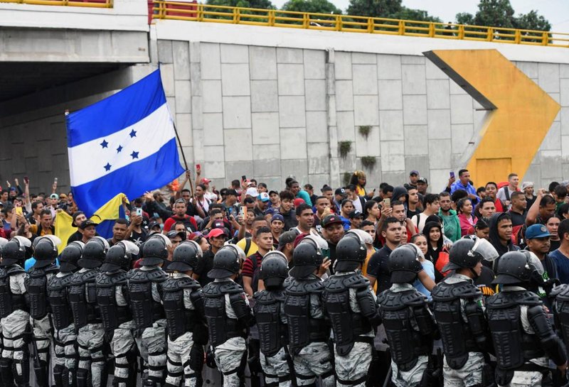 Gepanzerte Elemente der Nationalgarde bilden eine Kette vor einer Migrationskarawane. Es ist eine Fahne von Honduras zu sehen